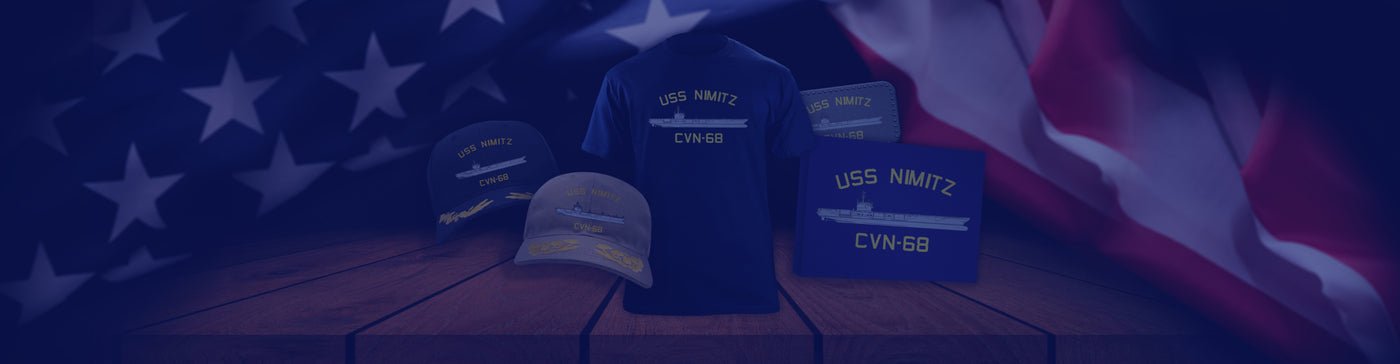 USS Nimitz apparel display with hats and shirts, American flag background.