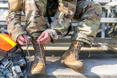 A soldier ties his boots before a ruck march.