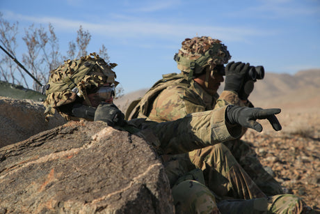Army soldiers assess targets using binoculars.