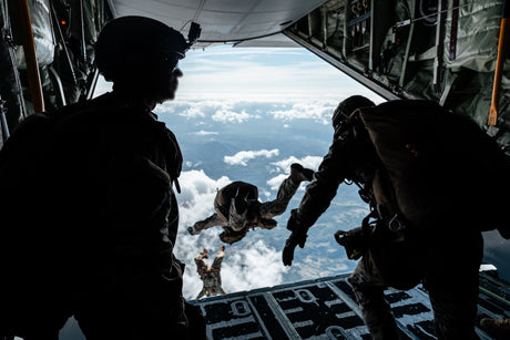 Airborne personnel exit an aircraft during a parachute jump.
