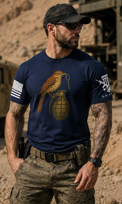 Limited Run T-Shirts - man in a navy grenade graphic tee and camo trousers beside a military vehicle.