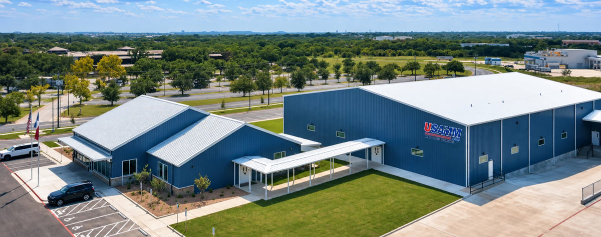 Aerial view of the USAMM headquarters in Killeen, Texas - a blue warehouse and showroom with American and Texas flags flying out front.